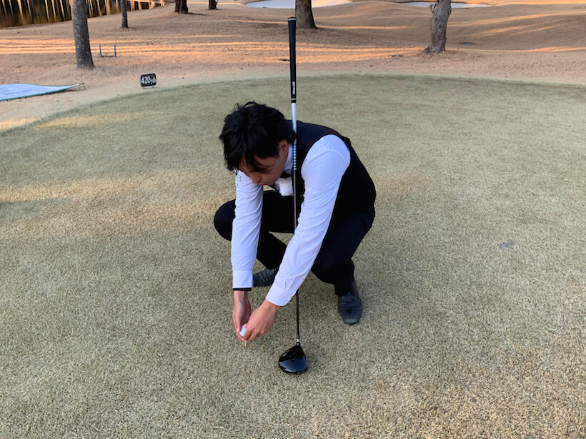 ゴルフ場での今野さんの写真,ボールを持ってしゃがみ込む