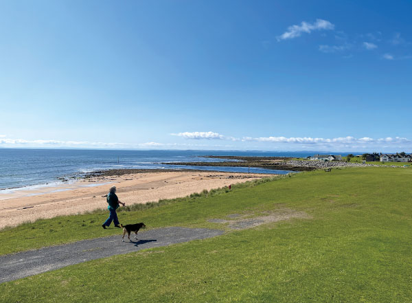 スコットランドのゴルフ場で犬と散歩を楽しむ人々